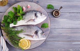 Raw dorado fish with green herbs cooking on cutting board. Top view photo