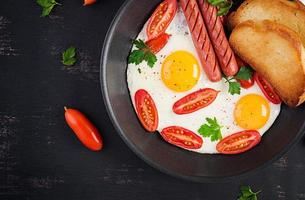 English breakfast - fried egg,  tomatoes, sausage,  and toasts. Top view, overhead photo