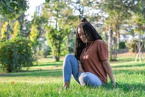 joven europeo mujer es sentado en un césped y haciendo yoga ejercicio. sano estilo de vida al aire libre. foto