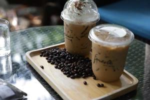 hielo café en un alto vaso con crema vertido terminado y café frijoles en un antiguo rústico de madera mesa. frío verano bebida en un oscuro de madera antecedentes con Copiar espacio foto