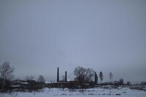 Winter landscape on cold day. Winter in Russia. View of field and factory. photo