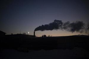 Smoke from chimney at night. View of factory in evening. Steam from boiler station pipe. photo