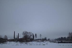 Winter landscape on cold day. Winter in Russia. View of field and factory. photo