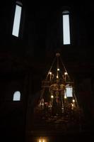 Interior of temple. Antique chandelier. Windows in dark. Lighting in church. photo