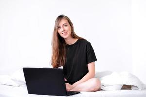 young woman working on laptop at home. work online. bed rest. freelancer girl works. photo