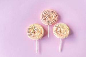 Pink round sweet meringues on a stick lie on a pink background photo