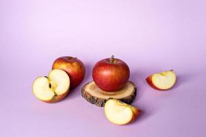 Red apples, whole and chopped, lie on a pink background photo