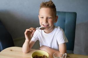 Cute boy eats a dry breakfast at home and smiles photo