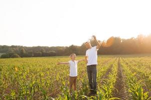 Cute boy in a cornfield with dad launching a plane photo