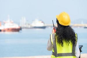 Asian Female Engineer Holding Walkie-Talkie with Marine Ship Background photo