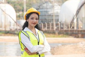 hembra ingeniero con casco de seguridad con petroquímico fábrica antecedentes. asiático mujer participación tableta, plan y walkie película sonora. foto