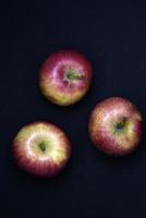Three red apples on a black background. Red and yellow apples. photo