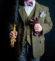 retrato de empresario en tweed traje participación paraguas y cuero guantes. Clásico estilo y retro Moda de elegante Inglés Caballero.