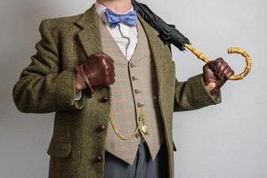 retrato de hombre en tweed traje participación paraguas terminado hombro. Clásico estilo de excéntrico Inglés Caballero. foto