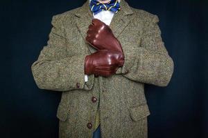 retrato de hombre en Clásico tweed traje tracción en cuero guantes en negro antecedentes. concepto de clásico y excéntrico británico Caballero