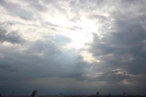 puesta de sol cielo encima pesado oscuro nubes casi lloviendo con dramático rayos de ligero brillante abajo antecedentes y ciudad noche hora foto