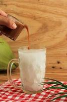 Pour Liquid Palm Sugar to Es Kelapa Muda, Young Coconut Ice photo