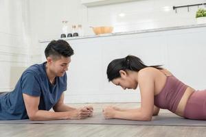 asiático Pareja broma ejercicio en piso juntos a hogar foto