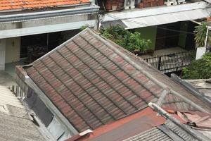 Oeste Jacarta, Indonesia - febrero 18, 2023 - antiguo rojo y polvoriento casa techo foto aislado con residencial casas antecedentes.