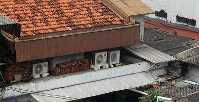 West Jakarta, Indonesia - February 18th, 2023 - Part of house roof, with a few ac air conditioner outdoor heating cooler isolated on house roof tops. photo