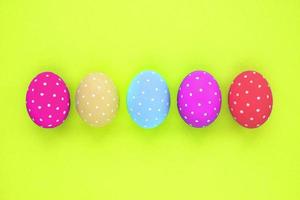 Easter coloured eggs with polka dot on neon yellow background. Flatlay postcard creative concept. Isolated decorated card, poster, banner, web, magazine. Minimal idea with copy space, close up spring photo