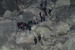 JAVA, INDONESIA - AUGUST, 9, 2016 - Miners carrying sulfur from Ijen Volcano Blue flames at night photo