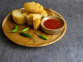 Fried casava or singkong goreng serve on a wooden plate with chilli sauce. boiled cassava then fried it. selected focus photo