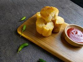 Fried casava or singkong goreng serve on a wooden plate with chilli sauce. boiled cassava then fried it. selected focus photo