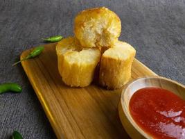 Fried casava or singkong goreng serve on a wooden plate with chilli sauce. boiled cassava then fried it. selected focus photo