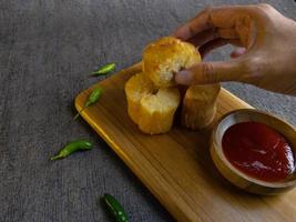 Fried casava or singkong goreng serve on a wooden plate with chilli sauce. boiled cassava then fried it. selected focus photo