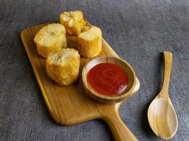 Fried casava or singkong goreng serve on a wooden plate with chilli sauce. boiled cassava then fried it. selected focus photo