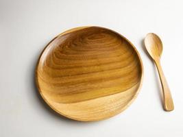 close up wooden plate and spoon isolated on white background. selected focus photo