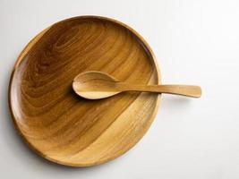 close up wooden plate and spoon isolated on white background. selected focus photo