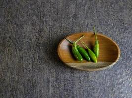 green chilli pepper or cabe rawit hijau in indonesian on a wooden plate. photo