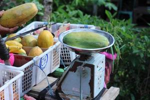 Papaya is weighed by an Indonesian vegetable seller photo