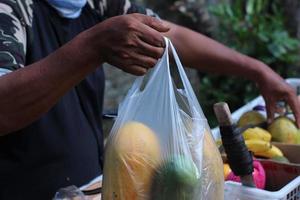 A peddler trader holding papaya plastic that has been weighed in Indonesia photo