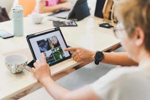 Business people working on laptop with hand pointing at screen in living room. photo