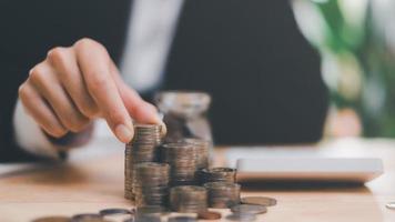 Accountant holding stack of money coins, Calculating company financial figures with a calculator, Analysis of company financial data, Planning to assess and review the budget, finance and investment photo