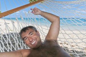 contento hombre relajante en hamaca en tropical paraíso playa foto