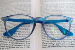 light blue reading glasses isolated on a book photo