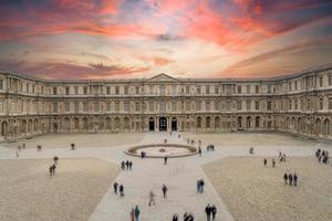 louvre museum exterior with tourist walking at sunset photo