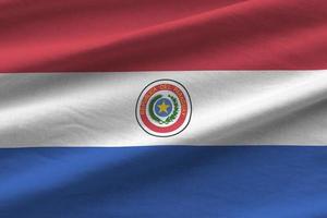 bandera paraguaya con grandes pliegues ondeando de cerca bajo la luz del estudio en el interior. los símbolos y colores oficiales en banner foto