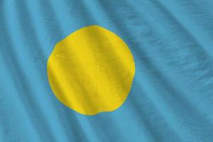 Palau flag with big folds waving close up under the studio light indoors. The official symbols and colors in banner photo