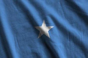 Somalia flag with big folds waving close up under the studio light indoors. The official symbols and colors in banner photo