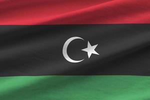 Libya flag with big folds waving close up under the studio light indoors. The official symbols and colors in banner photo