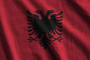 Albania flag with big folds waving close up under the studio light indoors. The official symbols and colors in banner photo