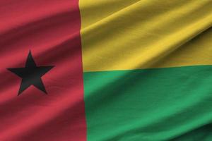 Guinea Bissau flag with big folds waving close up under the studio light indoors. The official symbols and colors in banner photo