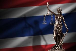 Thailand flag with statue of lady justice and judicial scales in dark room. Concept of judgement and punishment photo