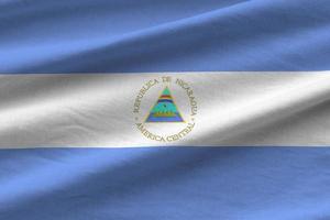 bandera de nicaragua con grandes pliegues ondeando de cerca bajo la luz del estudio en el interior. los símbolos y colores oficiales en banner foto