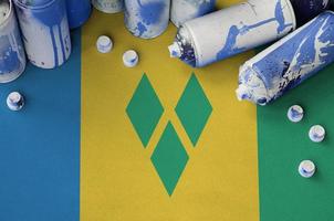 Saint Vincent and the Grenadines flag and few used aerosol spray cans for graffiti painting. Street art culture concept photo